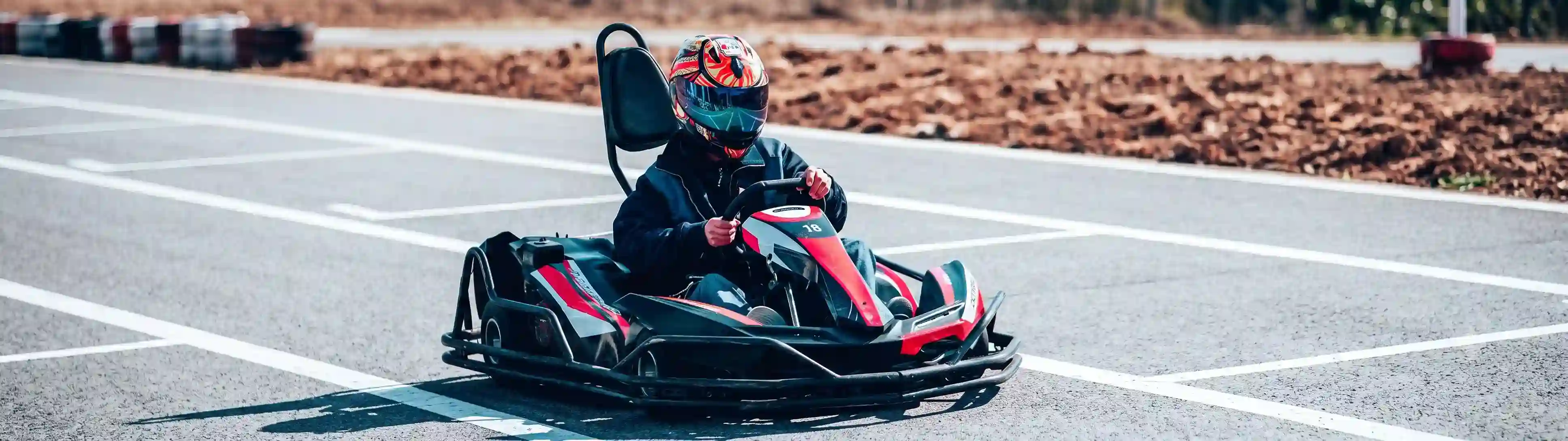 Go-kart driver racing on an outdoor track equipped with CYBER FIREBIRD remote speed control and safety technology.